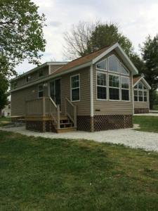 a small house with a porch and a large window at Circle M Camping Resort Loft Park Model 18 in Wabank