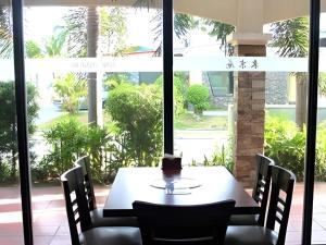 Una mesa y sillas frente a una gran ventana. en Bayfront Hotel Subic, en Olóngapo