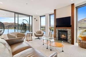 a living room with a fireplace and a tv at Sunlit Serenity Lakefront Apartment in Frankton
