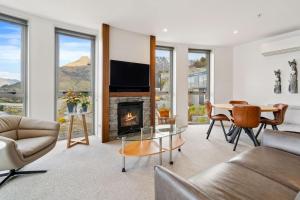 a living room with a fireplace and a table and chairs at Sunlit Serenity Lakefront Apartment in Frankton