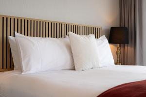 a bed with white pillows and a wooden headboard at Sunlit Serenity Lakefront Apartment in Frankton