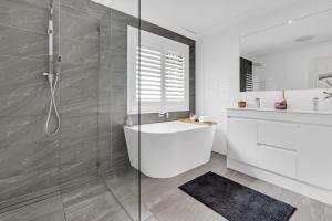 a bathroom with a shower and a tub and a sink at Beautiful Family House with Pool and BBQ in Gold Coast