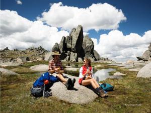 a man and woman sitting on a rock near a pond at Lake Kami Retreat - Jindabyne in Jindabyne