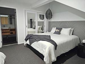 a bedroom with a large white bed and a bathroom at Lake Kami Retreat - Jindabyne in Jindabyne