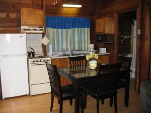 cocina con mesa, sillas y nevera blanca en Forest Lake Camping Resort Lakefront Cabin 8, en Freewood Acres