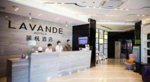 a lobby of a hotel with people standing at a counter at Lavande Hotel Yantai Train Station Branch in Yantai