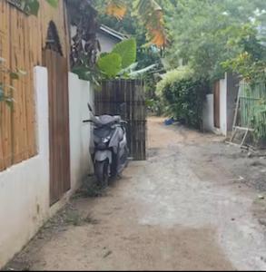 une moto garée à côté d'un bâtiment dans une cour dans l'établissement Caalan Cottage, à El Nido