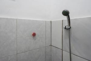 a shower with a red object on the wall at RedDoorz Syariah @ Hotel Wisma Indonesia Kendari in Kendari +39 photos