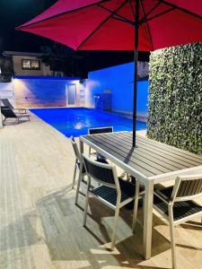 a picnic table with a red umbrella in front of a pool at FYV Beach Villas in San Juan