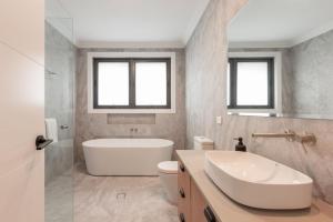 a bathroom with a tub and a toilet and a sink at The Riverside House in Burradoo +76 photos