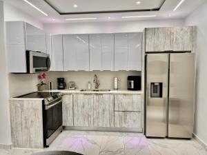 a kitchen with white cabinets and a stainless steel refrigerator at FYV Beach Villas in San Juan