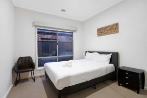 Un dormitorio con una cama y una silla y una ventana. en Family Home with Home Theater in Tarneit, en Tarneit