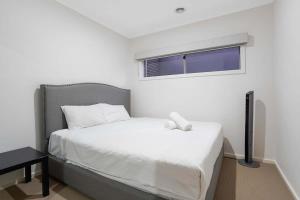Un dormitorio pequeño con una cama blanca y una ventana. en Family Home with Home Theater in Tarneit, en Tarneit