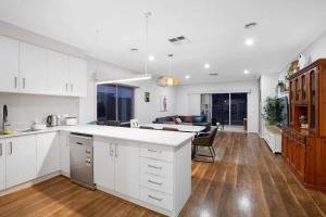 Una cocina con gabinetes blancos y una sala de estar. en Family Home with Home Theater in Tarneit, en Tarneit
