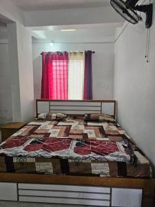 a bedroom with a bed with a red curtain at Hamai nisha villa in Ambalavayal