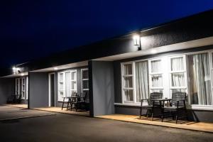 ヘイスティングズにあるFrimley Lodge Motel - with Airport Shuttle service- Best Location in Townの椅子とテーブルと夜の窓のあるパティオ