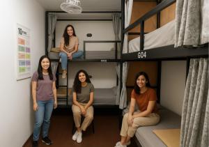 a group of women sitting in a room with bunk beds at Beanstay hostel in Phuket