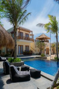 a villa with a swimming pool and palm trees at Statler Private Beach Villa Mandalika in Kuta Lombok