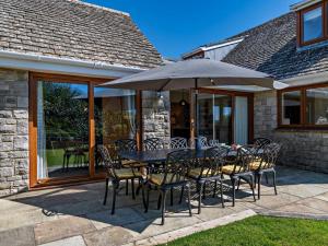 ein Tisch und Stühle mit einem Sonnenschirm auf einer Terrasse in der Unterkunft 5 Bed in Worth Matravers DC142 in Worth Matravers