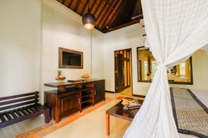ein Zimmer mit einem Bett, einem Tisch und einem Fernseher in der Unterkunft Barong Resort Ubud by Puri Signatures in Ubud