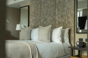 Un dormitorio con una cama con almohadas blancas y un espejo. en The Lyall, en Melbourne