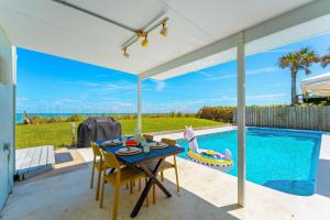 a patio with a table and chairs next to a swimming pool at 5435 Highway A1A in Melbourne Beach
