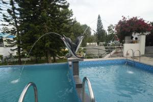a swimming pool with a statue of a dolphin at WOW Naturefull Resorts in Yercaud