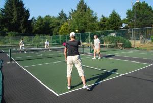 Seaside Camping Resort Studio Cabin 3 في سيسايد: مجموعة من الناس يلعبون التنس على ملعب تنس