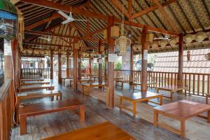 a restaurant with wooden tables and benches in a room at RedDoorz @ Kampoeng Etnik Kebumen 2 in Kebumen