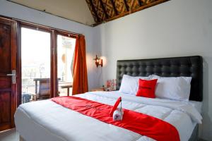 a dog laying on a bed with a red blanket at RedDoorz @ Kampoeng Etnik Kebumen 2 in Kebumen +38 photos