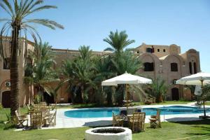 a resort with a swimming pool with chairs and umbrellas at Hotel Talid in Siwa