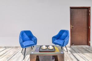 two blue chairs and a table in a room at Super Hotel O Clock Tower Dehradun Formerly Dooncity Suites in Dehradun