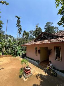een kind dat op een fiets voor een huis zit bij River stream Nest homestay in Madikeri +14 foto's