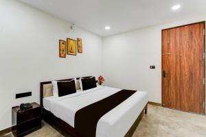 a bedroom with a large bed and a wooden door at Super Townhouse OAK Owaisi Hospital Mailardevpally Formerly Tolkanti Arc in Haidar Sāhibgūda +24 photos