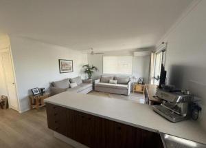 Beachside Getaway in Sunny Palm Beach في غولد كوست: مطبخ وغرفة معيشة مع أريكة وطاولة