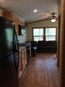 a kitchen with a black refrigerator and a couch at Circle M Camping Resort Screened Park Model 27 in Wabank