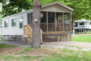 a house with a porch and a tree at Circle M Camping Resort Screened Park Model 27 in Wabank