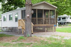 a house with a porch and a tree at Circle M Camping Resort Screened Park Model in Wabank