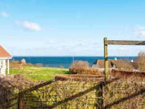 a fence with the ocean in the background at 6 person holiday home in Augustenborg in Augustenborg +49 photos