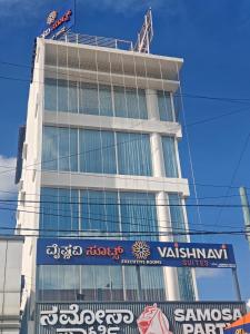 un grand bâtiment avec une enseigne devant dans l'établissement Vaishnavi Suites, à Bangalore