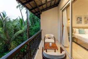 a balcony with a bed and a table and a chair at Lamrin Morjim Goa in Morjim