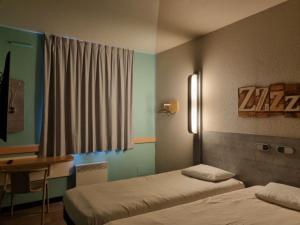 a room with two beds and a desk and a window at ibis budget Albertville in Gilly-sur-Isère +63 photos