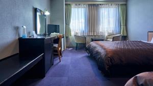 a hotel room with a bed and a desk at Hotel Satsukien in Kanoya