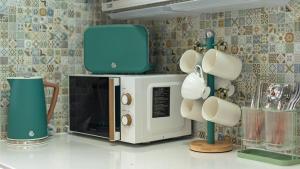 a microwave sitting on a kitchen counter with mugs at Seogwipo Pyoseon Doldamjip in Pyoseon