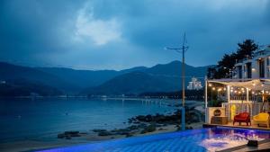 a house with a swimming pool next to a body of water at Namhae Melody Kids Private Pension in Sukho +41 photos