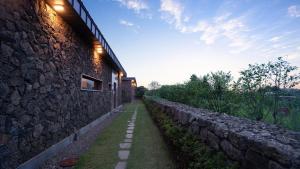 a stone wall next to a building with a pathway at Seogwipo Pyoseon Doldamjip in Pyoseon