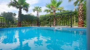 a swimming pool with a fence and palm trees at Seogwipo Pyoseon Doldamjip in Pyoseon