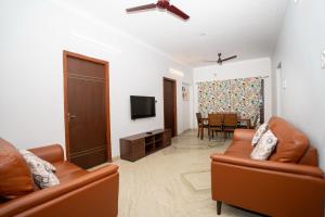 a living room with two leather couches and a television at Cozy 2BR in Chennai