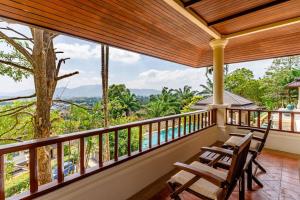 d'un balcon avec deux chaises et une vue sur la forêt. dans l'établissement Luxurious Phuket Escape - Lakewood Hills, à Layan Beach