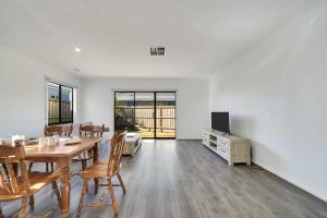 a dining room with a table and chairs and a tv at Modern Comforts in a Spacious 3BR Family Retreat in Rockbank